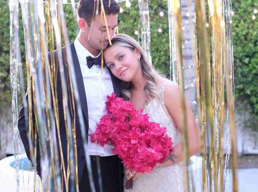 Couple with fuchsia flower bouquet lean against each other