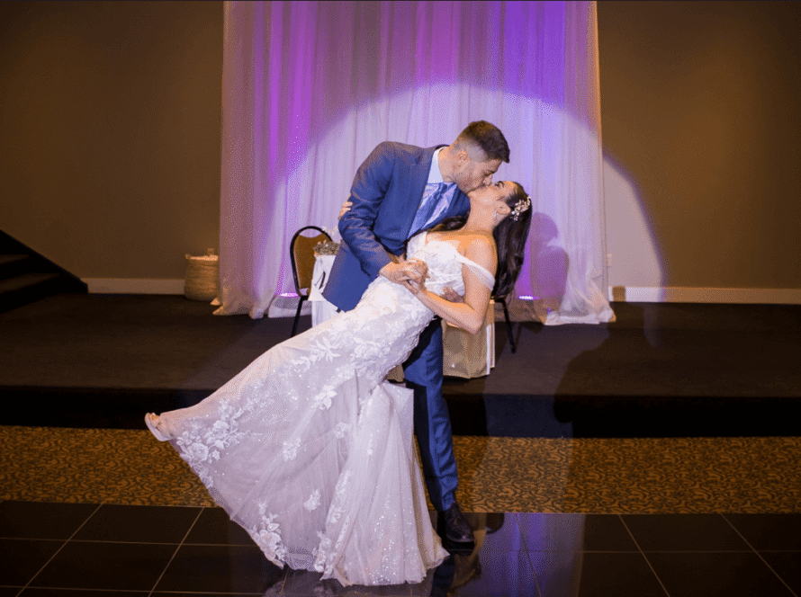 groom dips bride for a kiss in balconade room