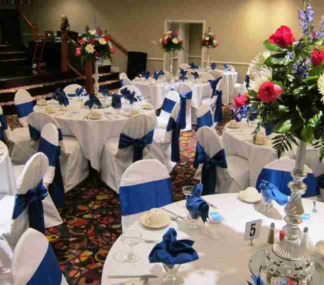 Terrace Room blue chair sashes and linen napkins with red rose centerpieces