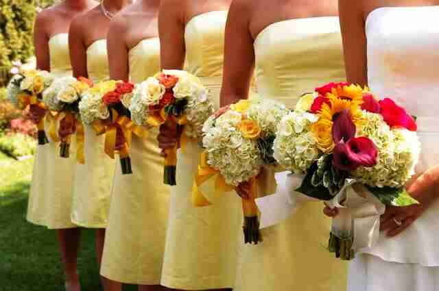 lineup of bridesmaids wearing wearing yellow dresses and holding floral bouquets